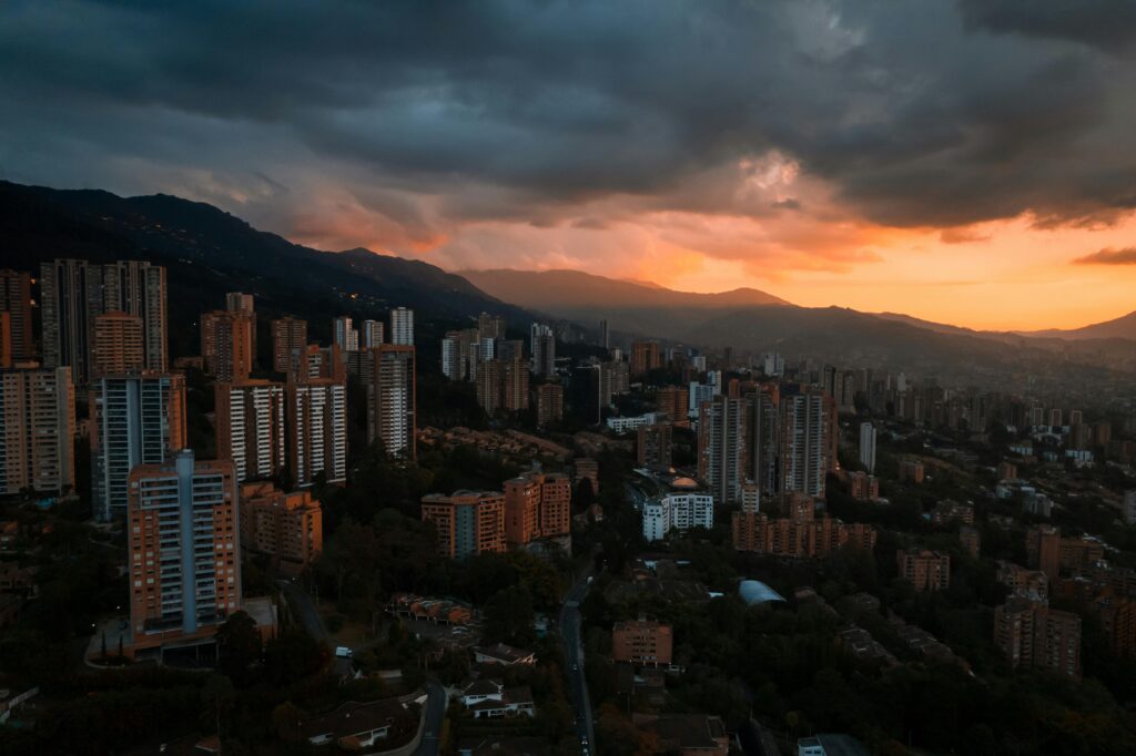 Stunning aerial view of Medellín's skyline at sunset with dramatic cloud formations creating a moody atmosphere.